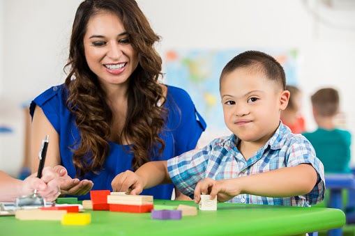 Hispanic Down Syndrome child playing with blocks at daycare