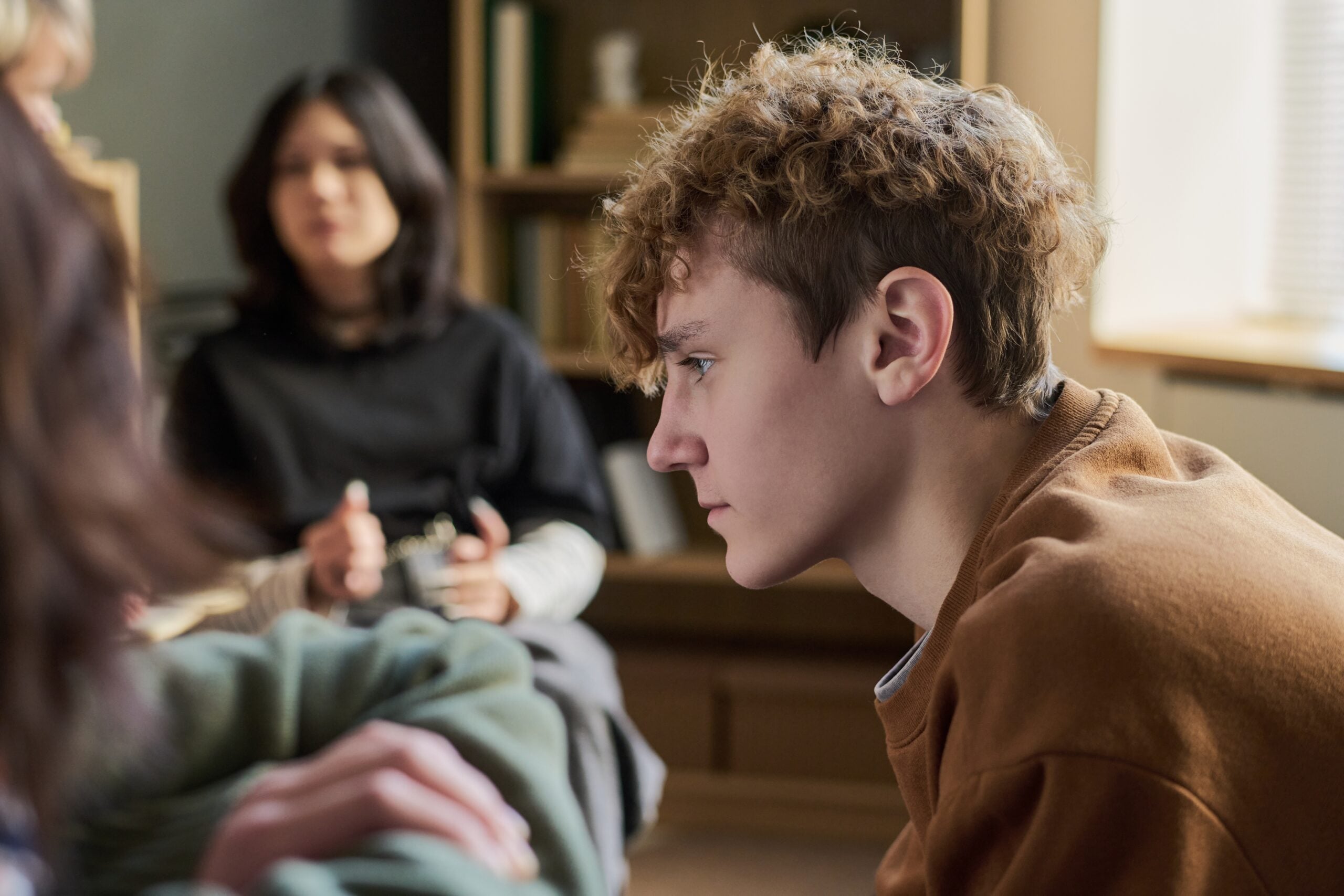 Teenager,Boy,Sitting,In,Profile,Listening,Attentively,During,Group,Therapy